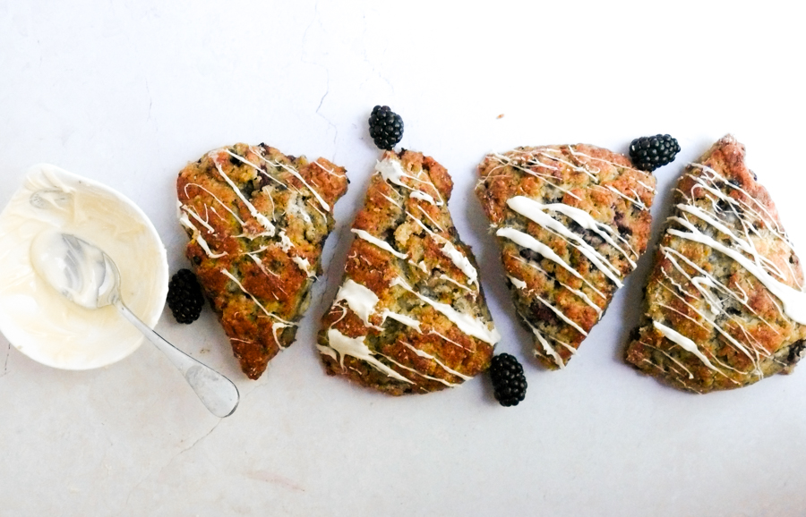 4 blackberry scones with a white chocolate drizzle in a horizontal shot