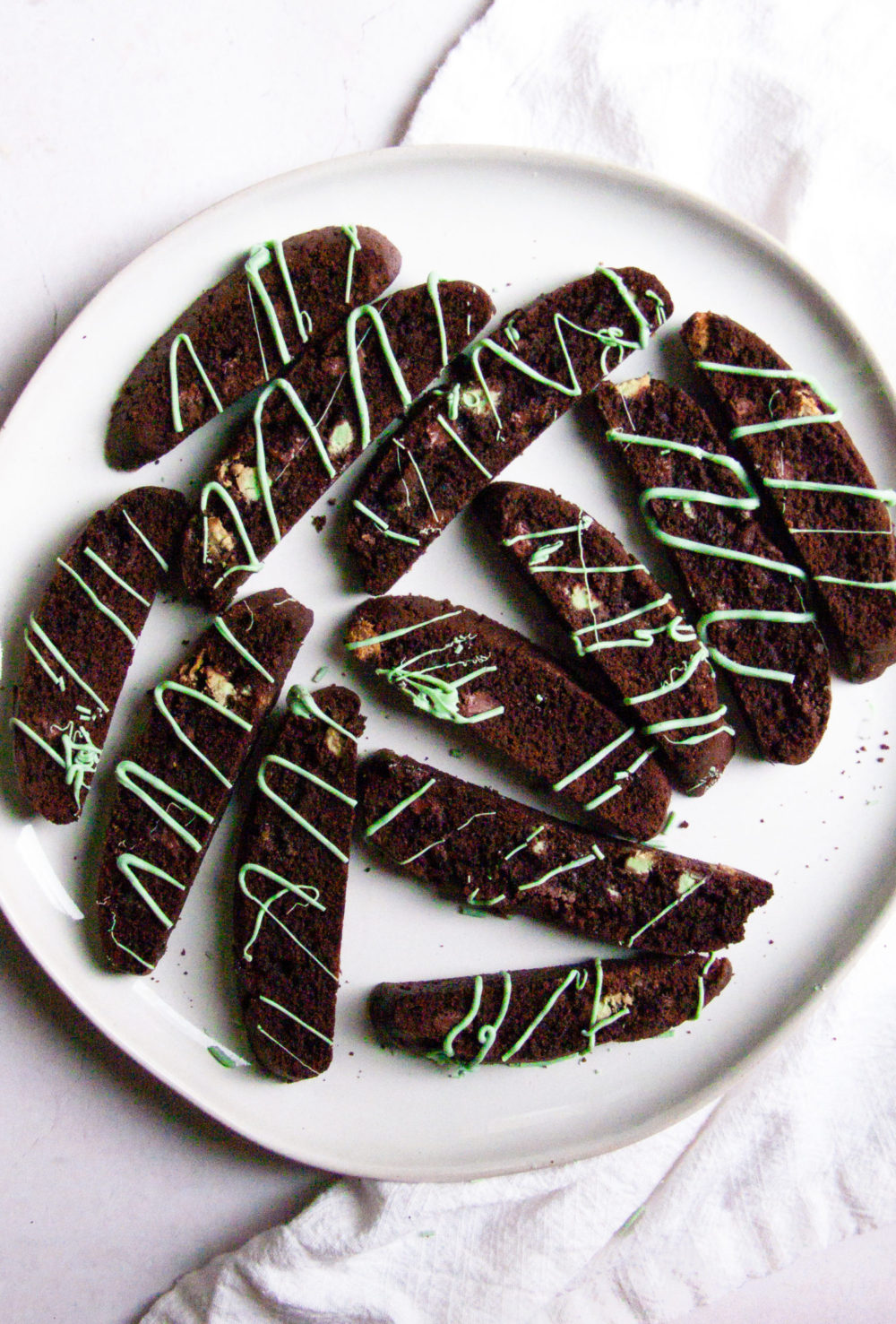 Multiple mint cookies on a plate surrounded by a linen