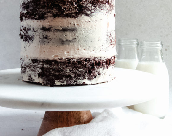 The full mocha cake on a marble cake stand with milk bottles in the background
