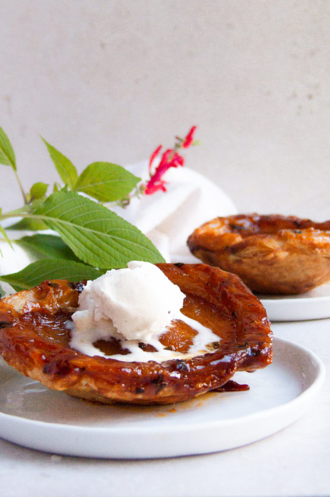 45º angle shot of the puff pastry tarts with sage in the back and ice cream on top