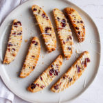All the biscotti laid out on a white plate drizzled with white chocolate