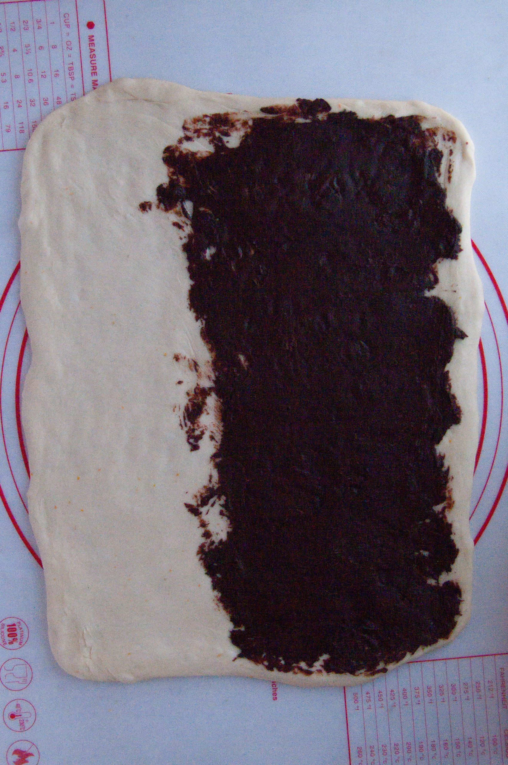 rolled out bun dough with chocolate filling spread onto it