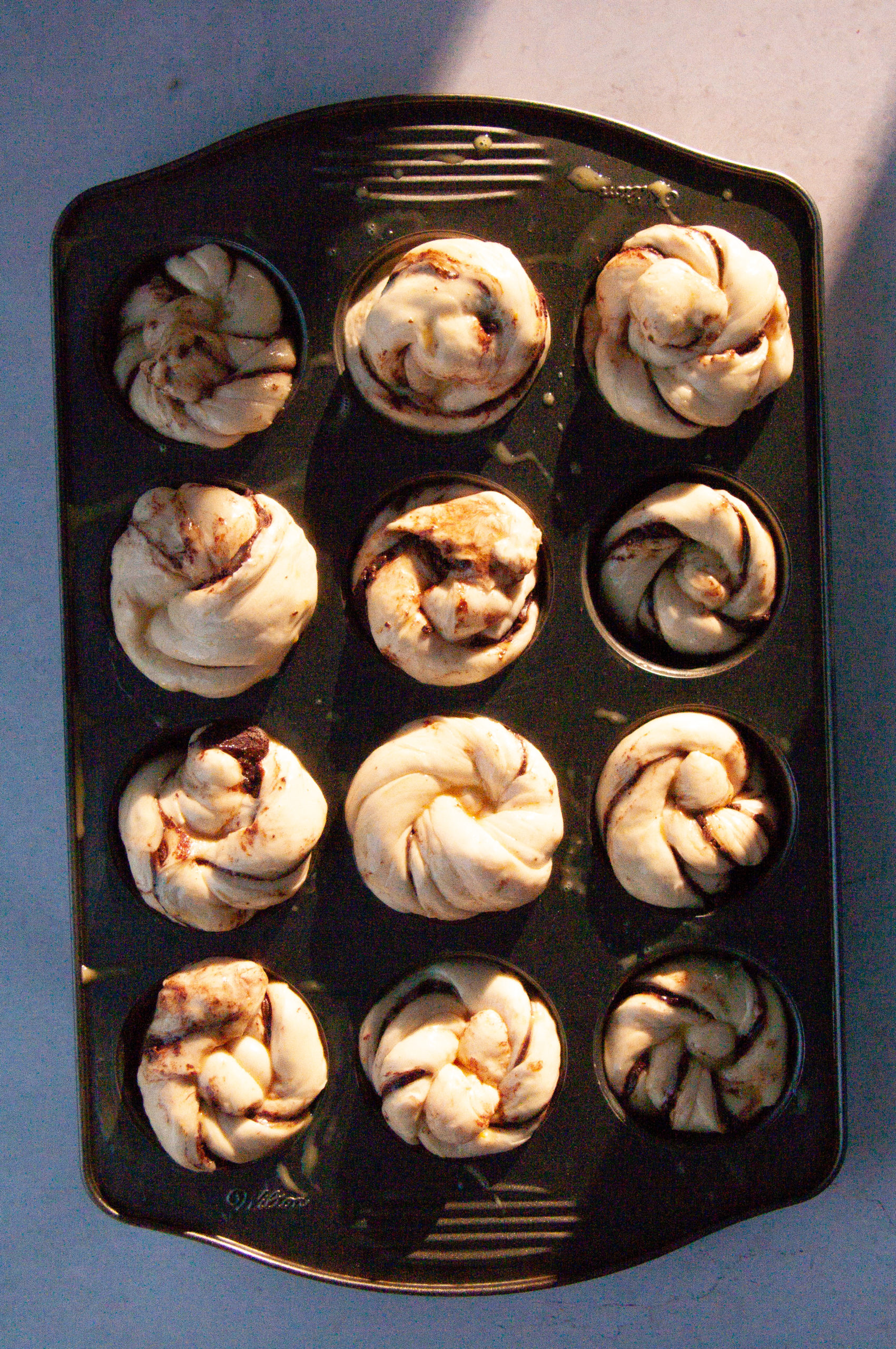assembled orange buns on a dark muffin tin