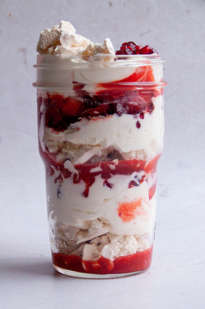 individual shot of eton mess with pom syrup, whipped cream, and berries